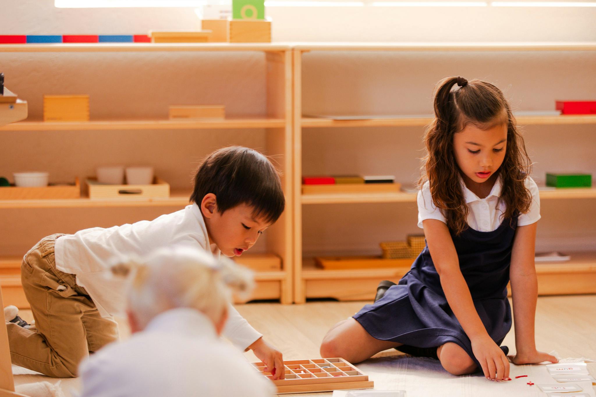 Two children playing with educational materials on the floor