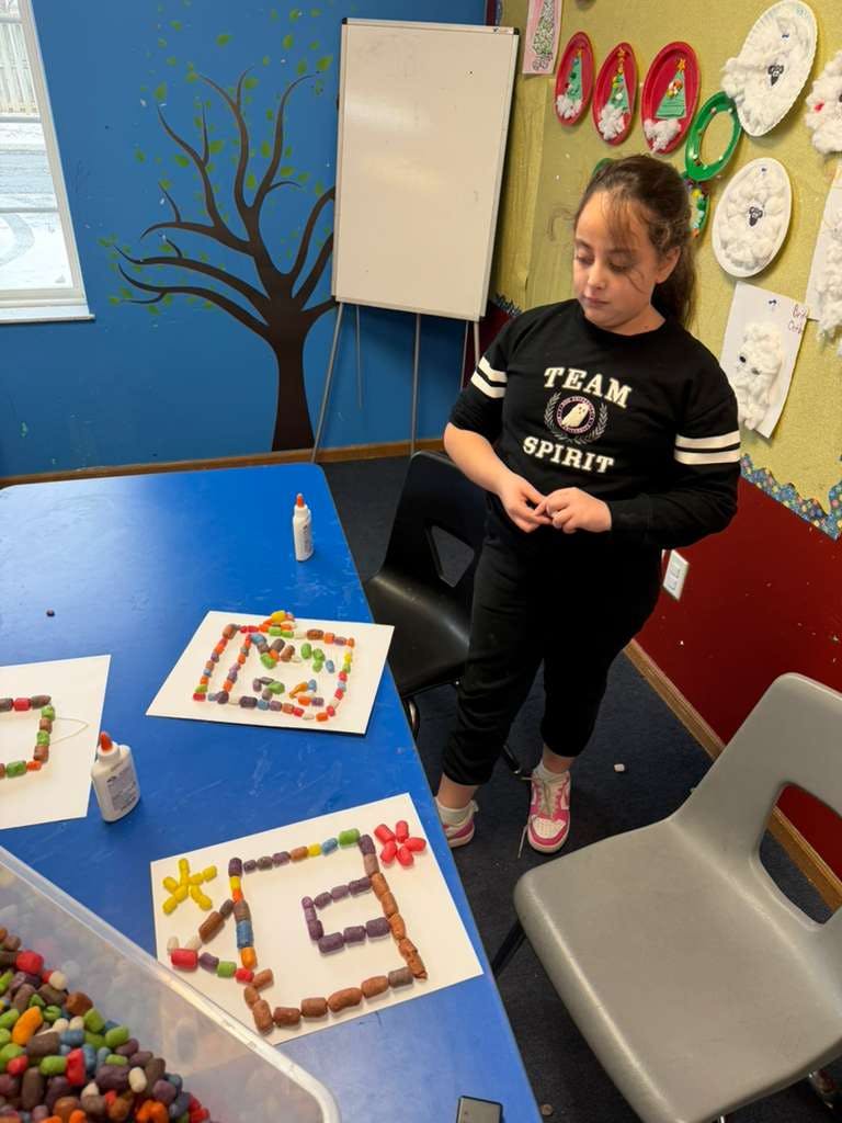 Child looking at an art project made from colorful cereal pieces