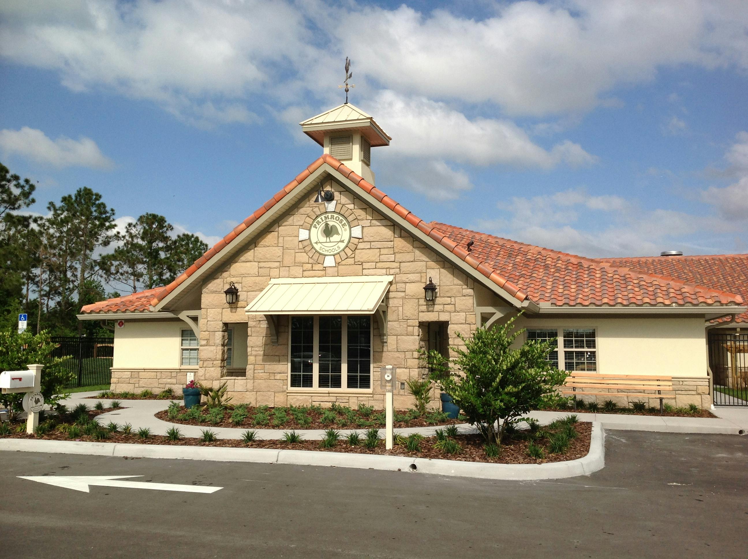 Building with a stone facade, red tile roof, and small cupola