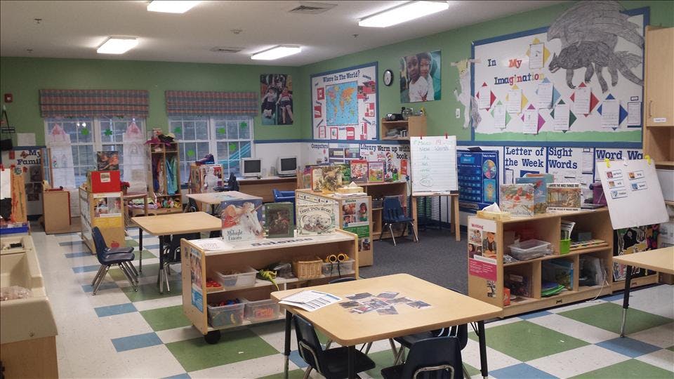 A classroom with tables, chairs, teaching materials, and a world map