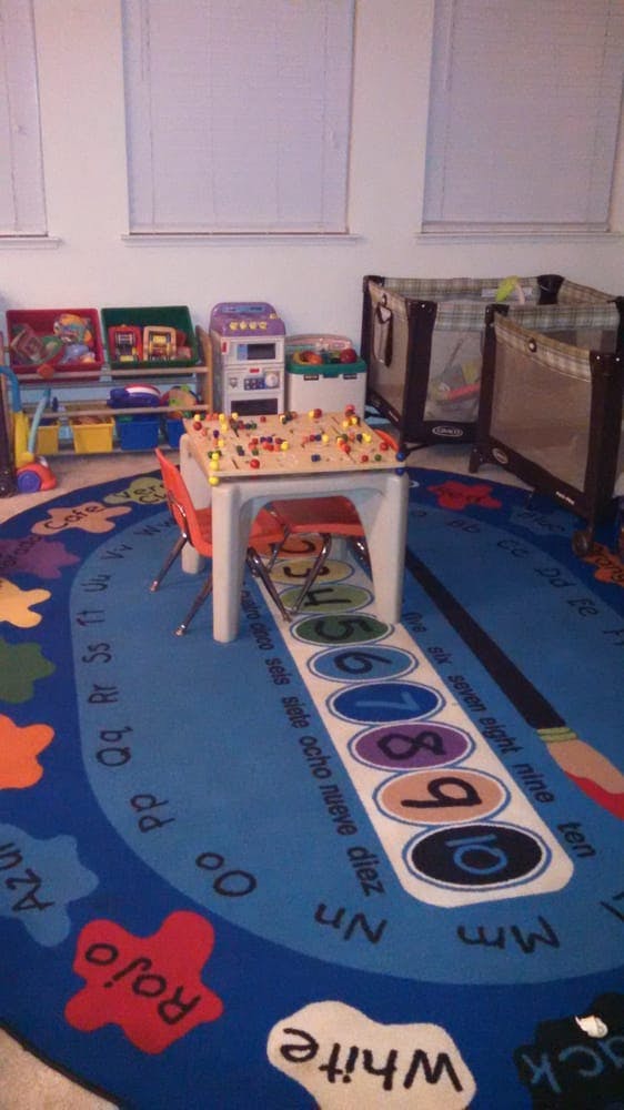 Playroom with a colorful rug, small table, and cribs