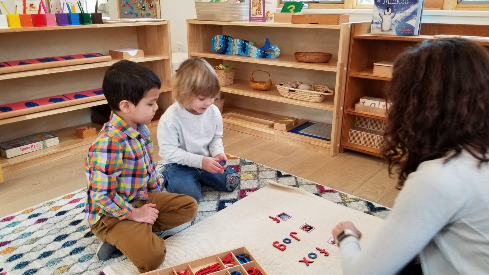Adult and two children on floor with letter tiles