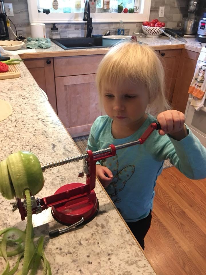 Child using an apple peeler in a kitchen