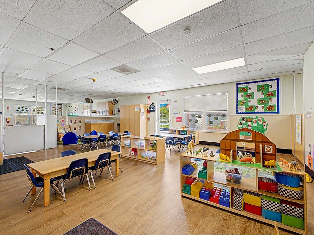Classroom with child-sized tables and chairs and a play barn with animal figures