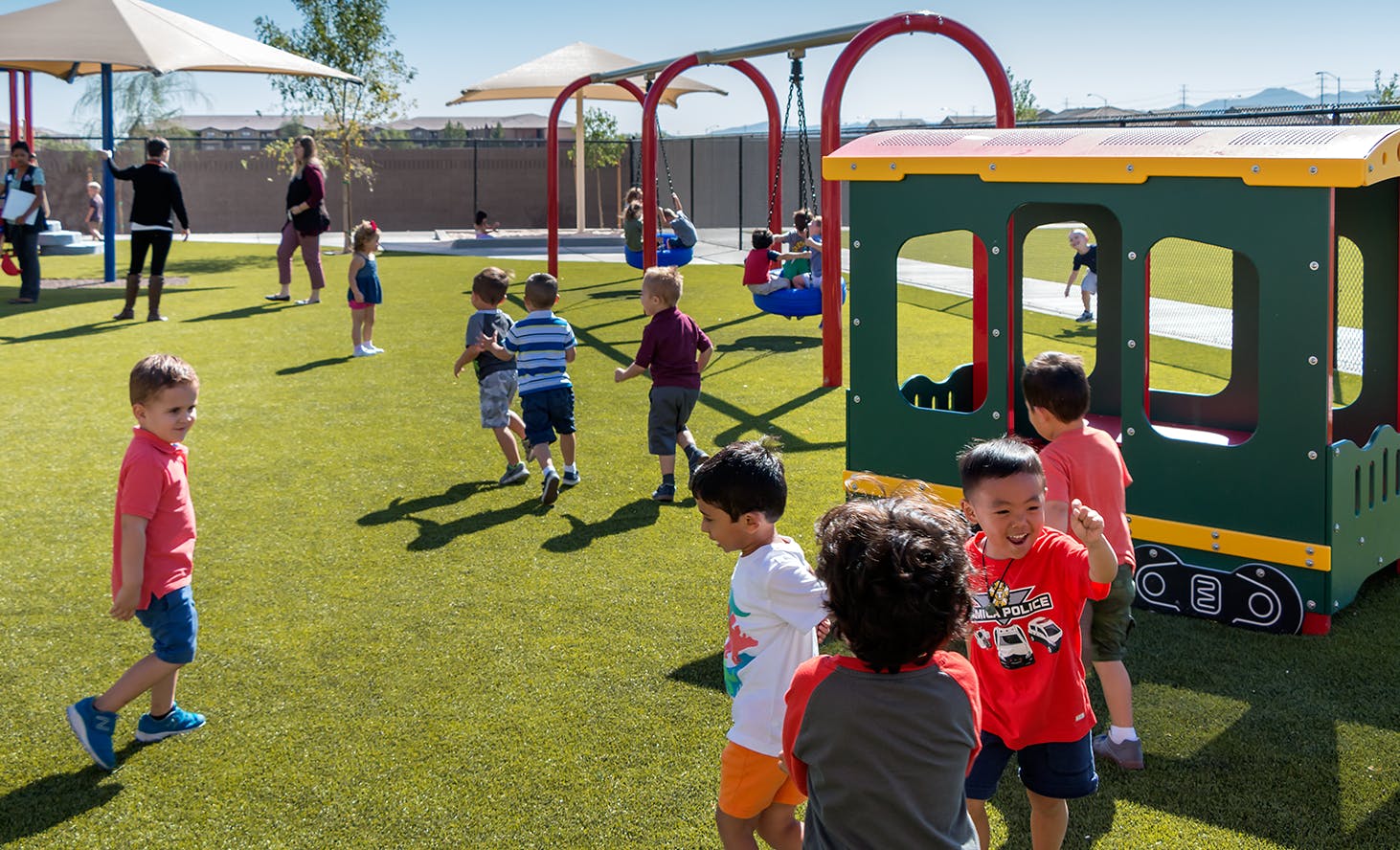 Children playing on a playground with swings and a train structure