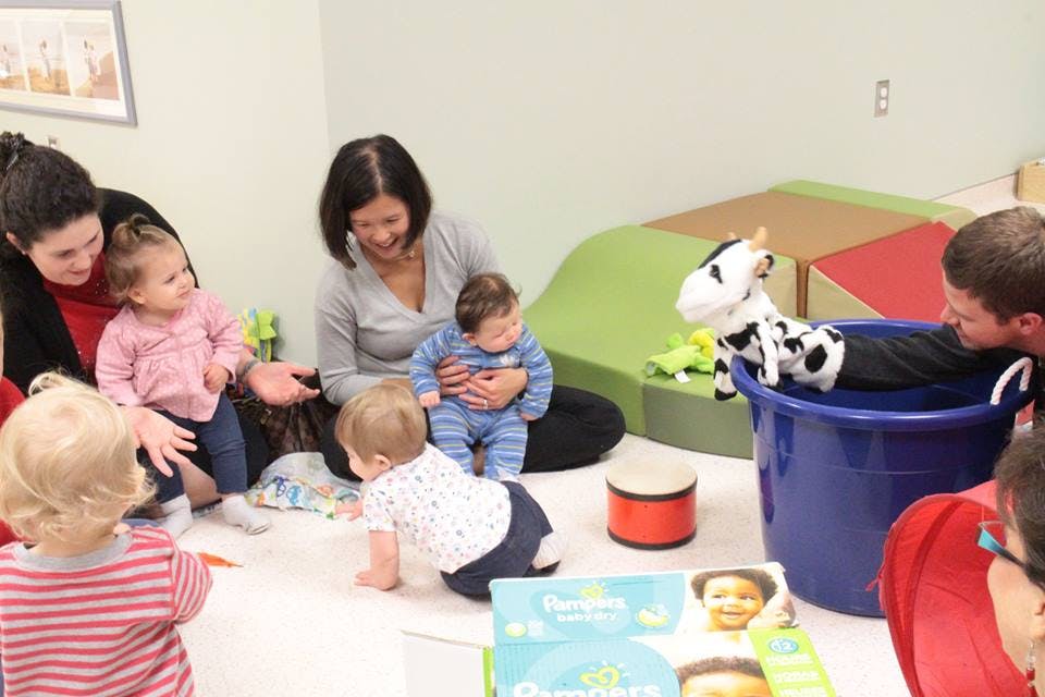 Adults and children playing on the floor with toys