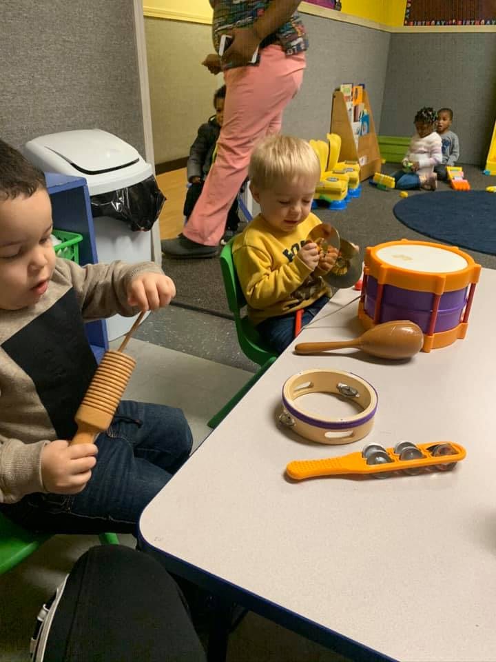 Two children playing with musical instruments in a classroom