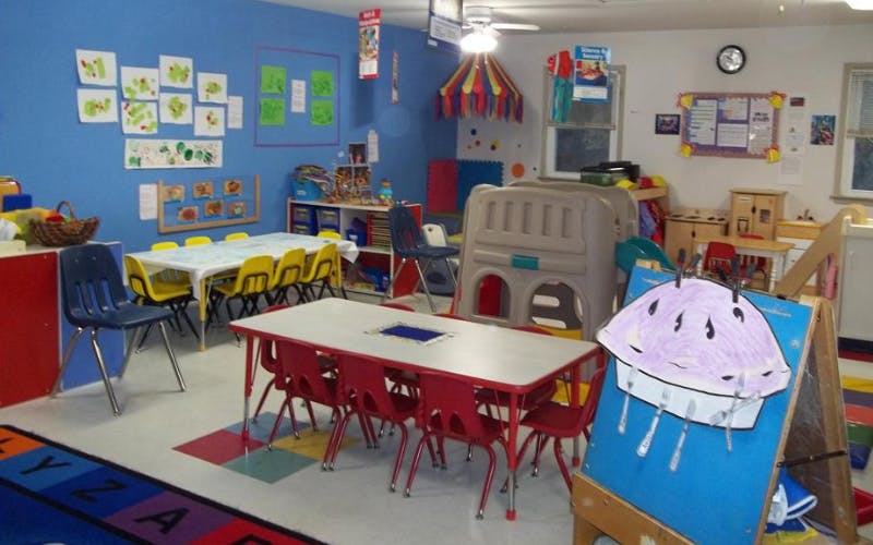 A classroom with tables and chairs for children, artwork on the walls