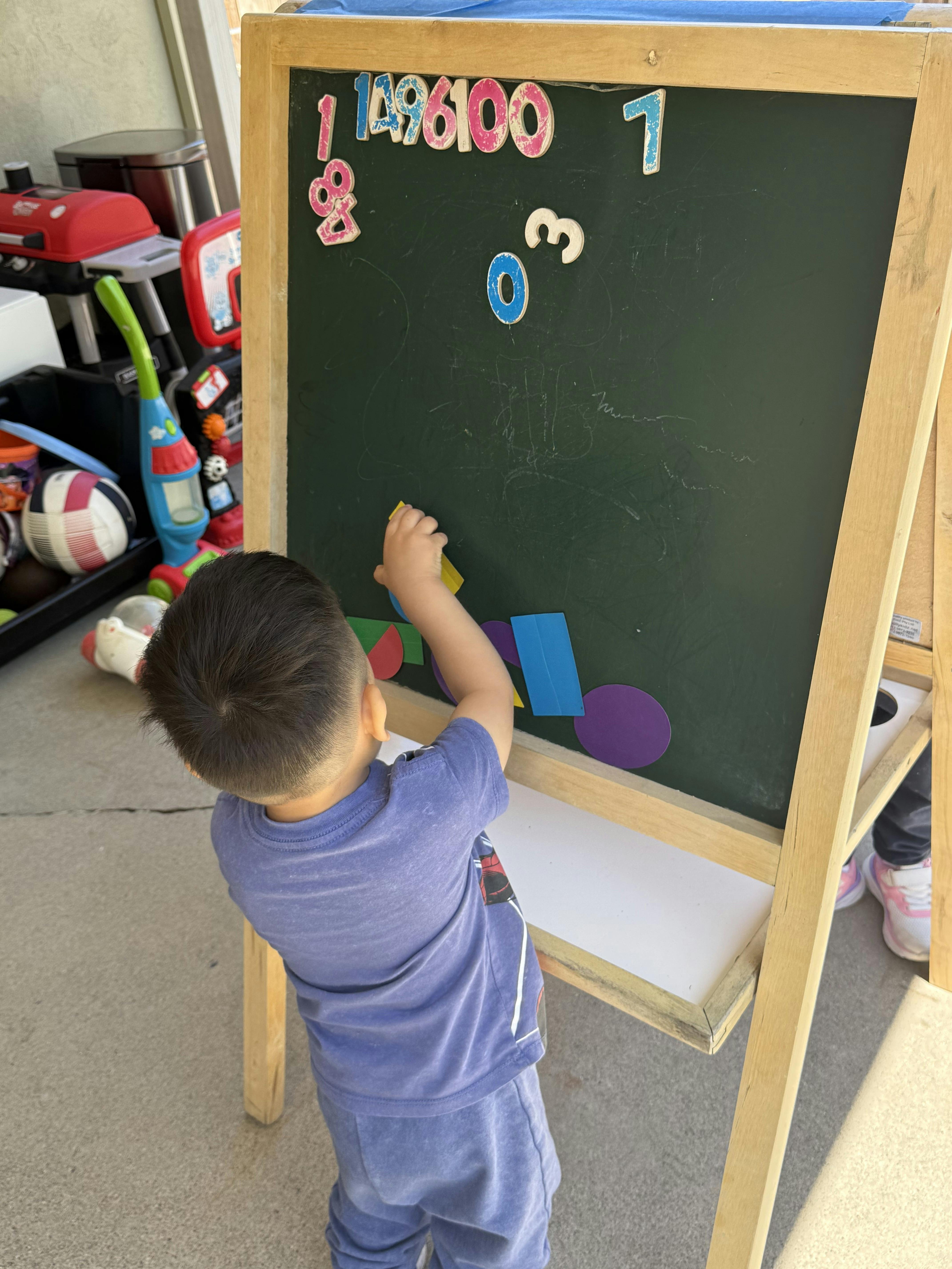 Child placing colorful foam shapes on a magnetic chalkboard