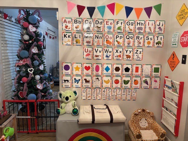 Decorative wall with alphabet cards, numbers, shapes, and colors, colors in the foreground, a Christmas tree