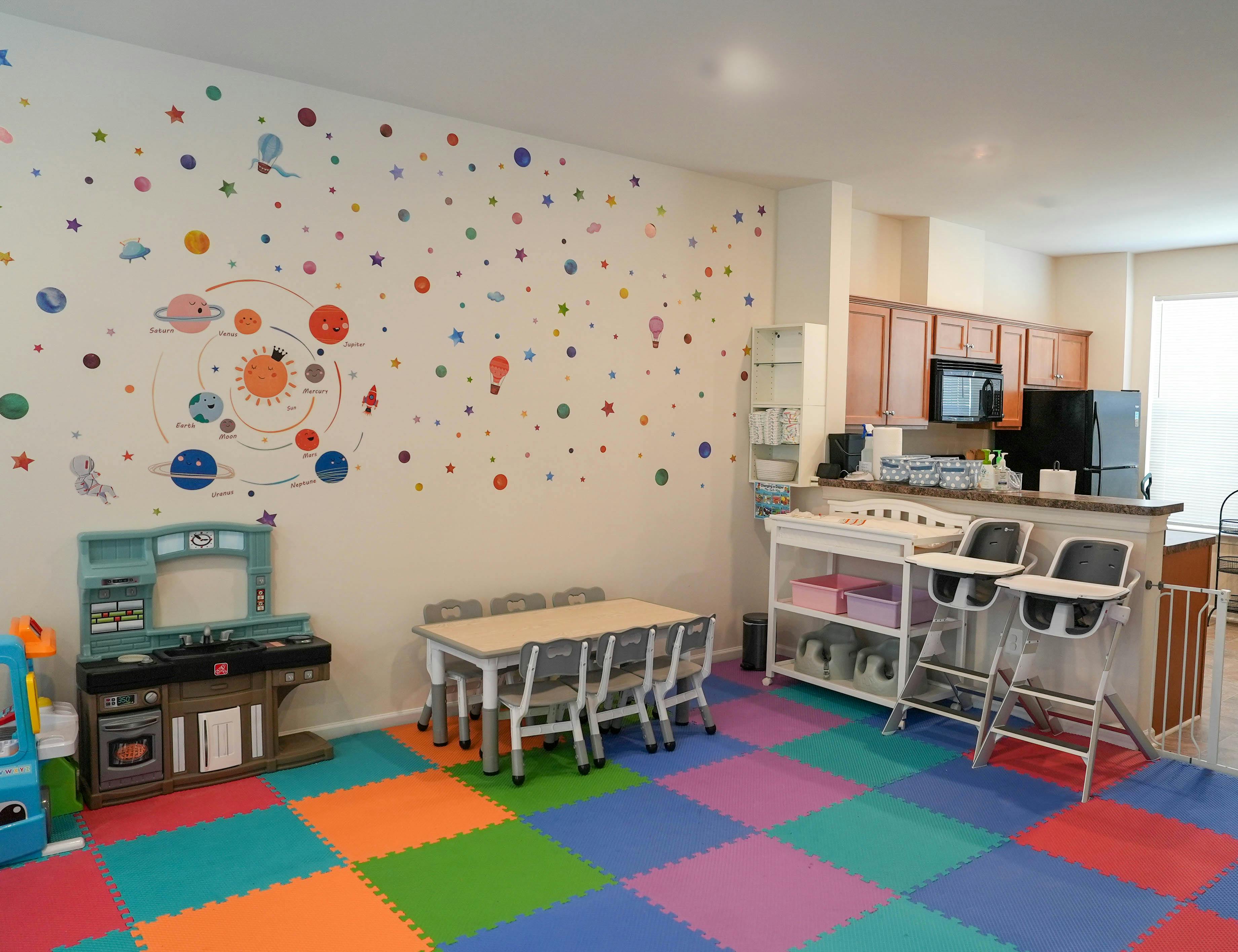 Playroom with colorful floor, small table and chairs, and kitchen area