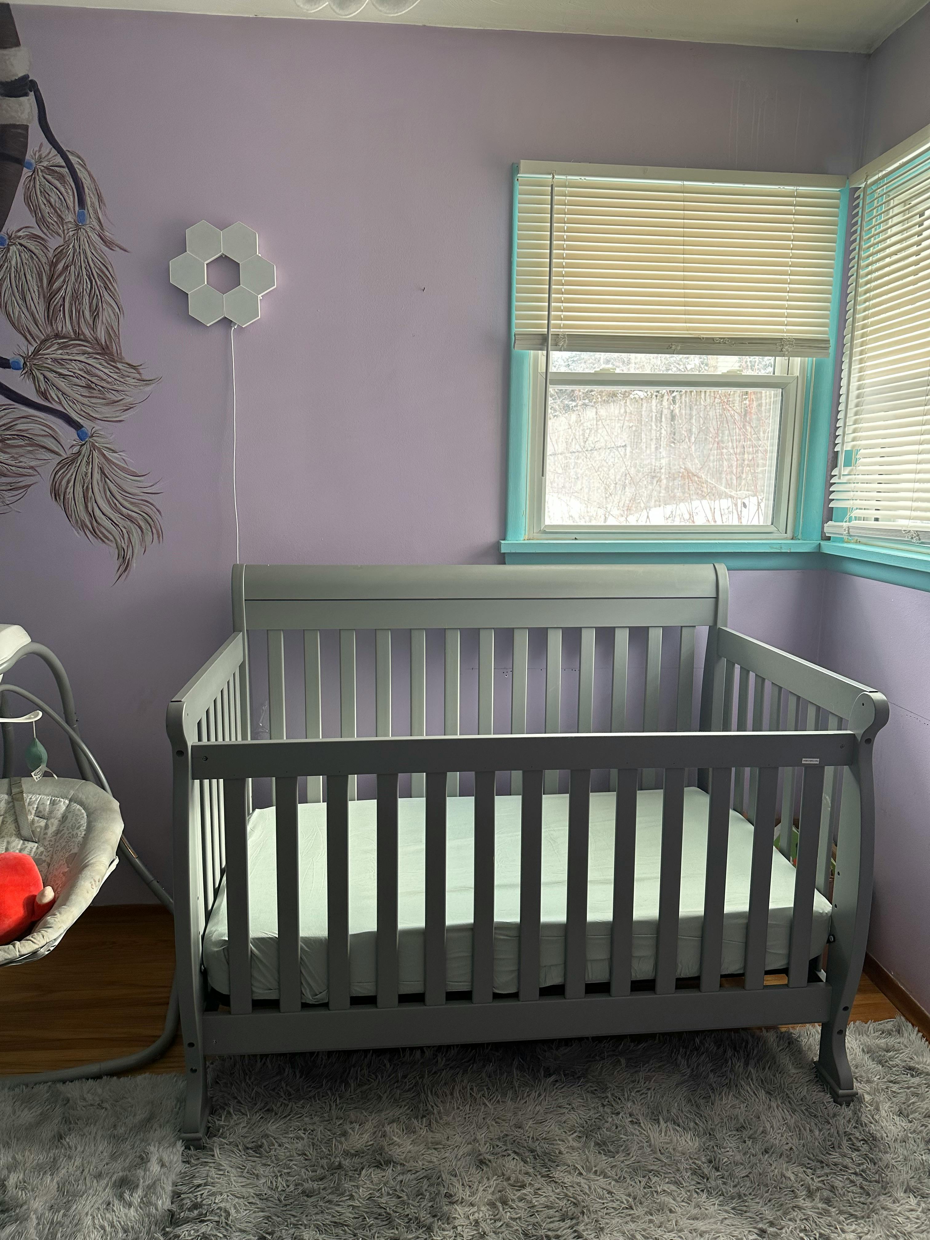 Empty crib in a room with purple walls