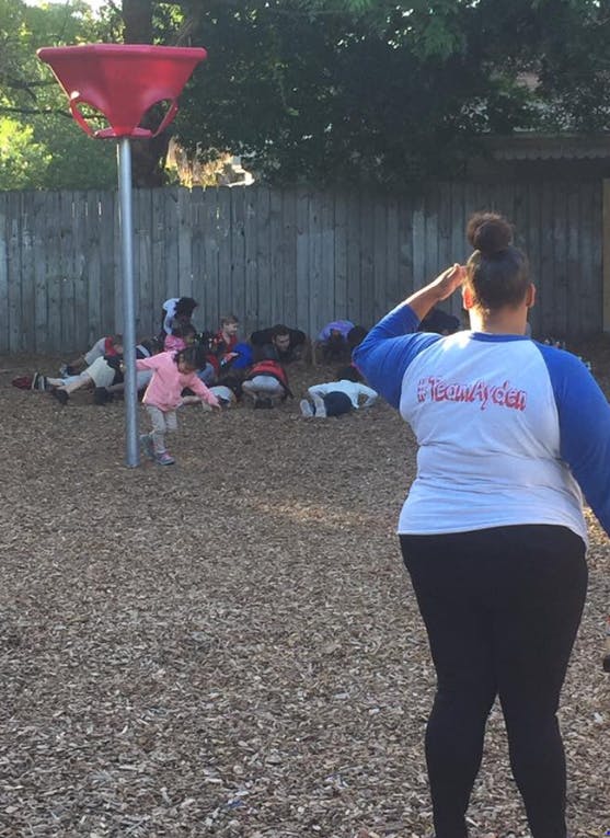 Person saluting with children on the ground in the background