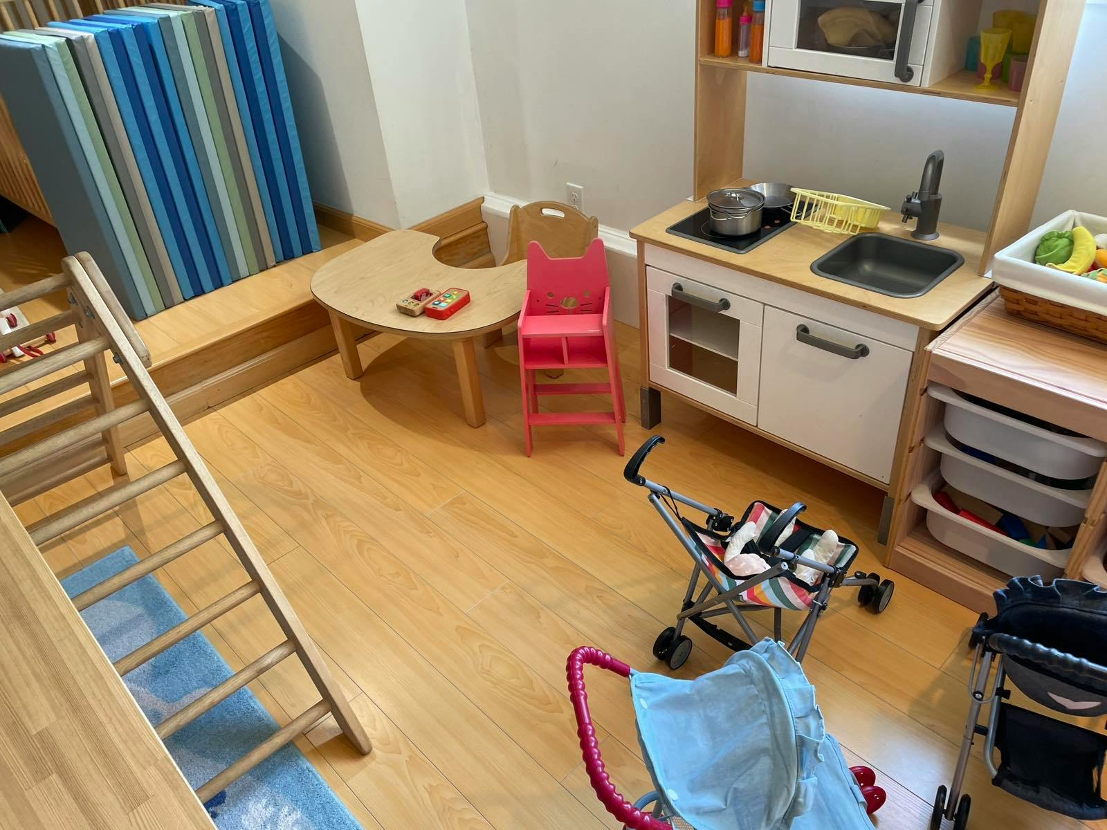 Playroom with toy kitchen, table, chairs, and strollers
