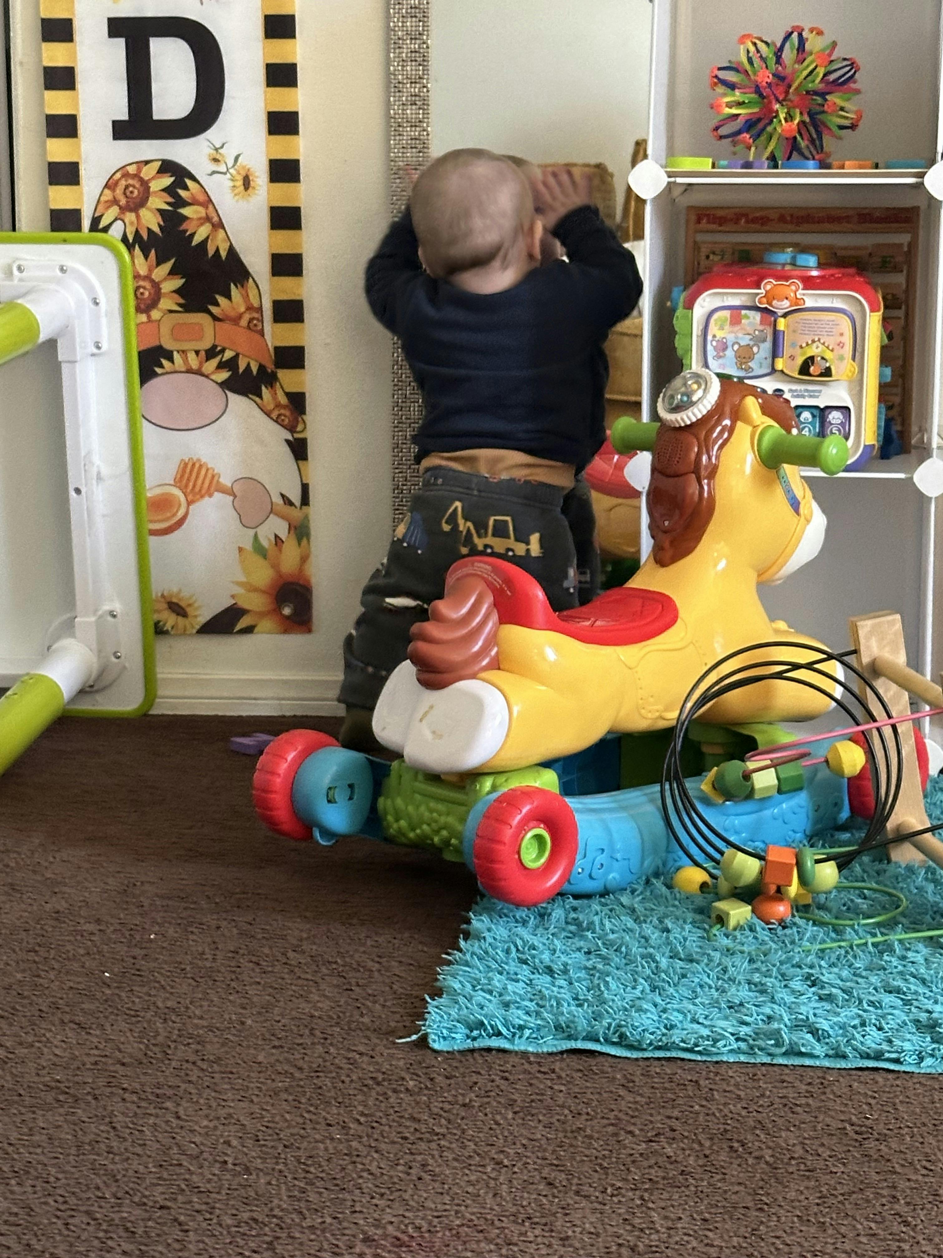Child standing next to a toy horse