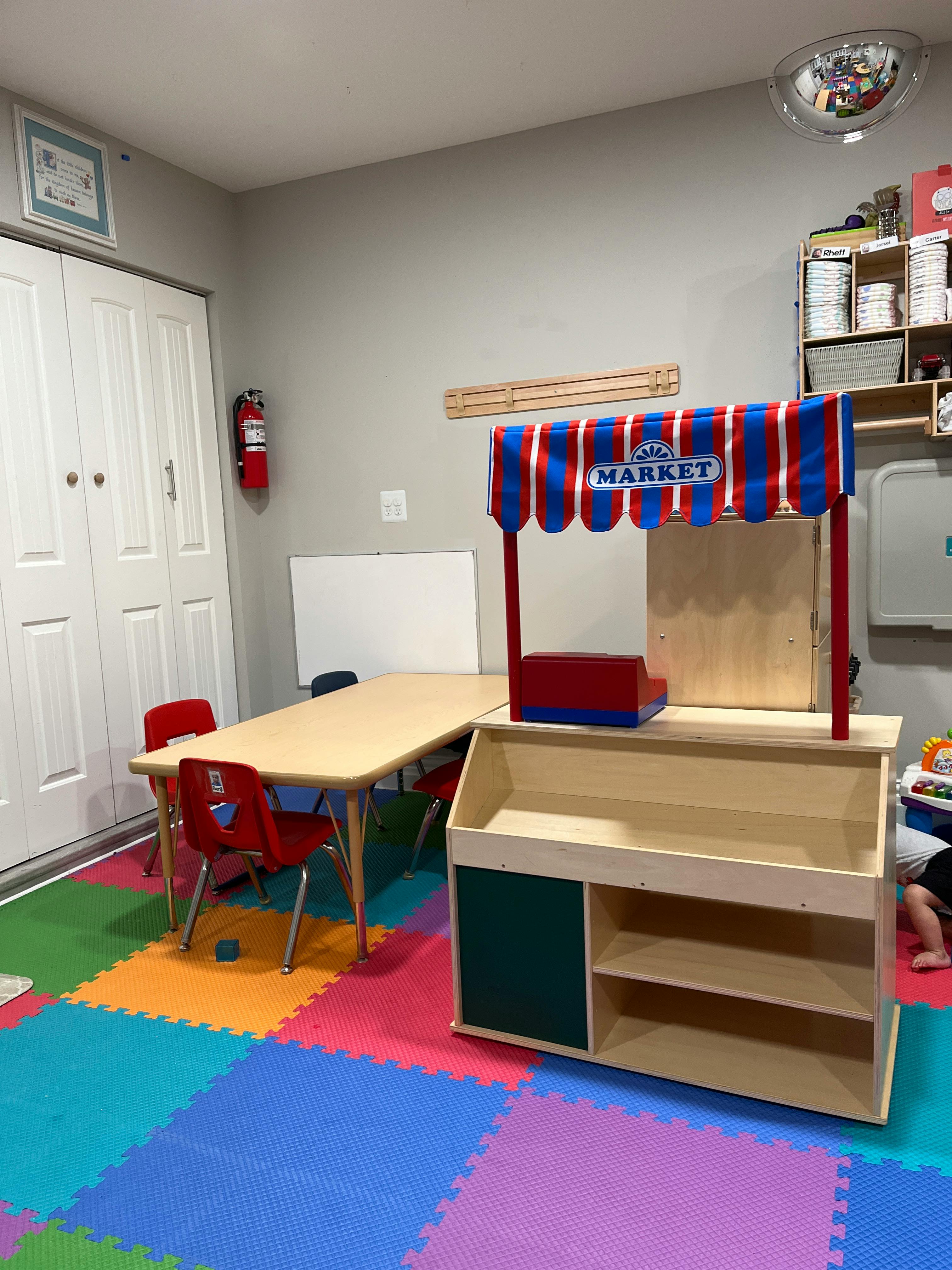 Play market stall and child sized table in a room with floor mats