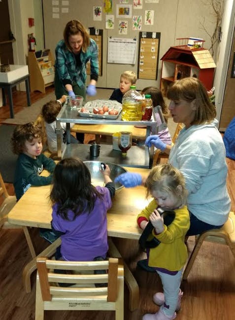 Adults and children gathered around a table with food items
