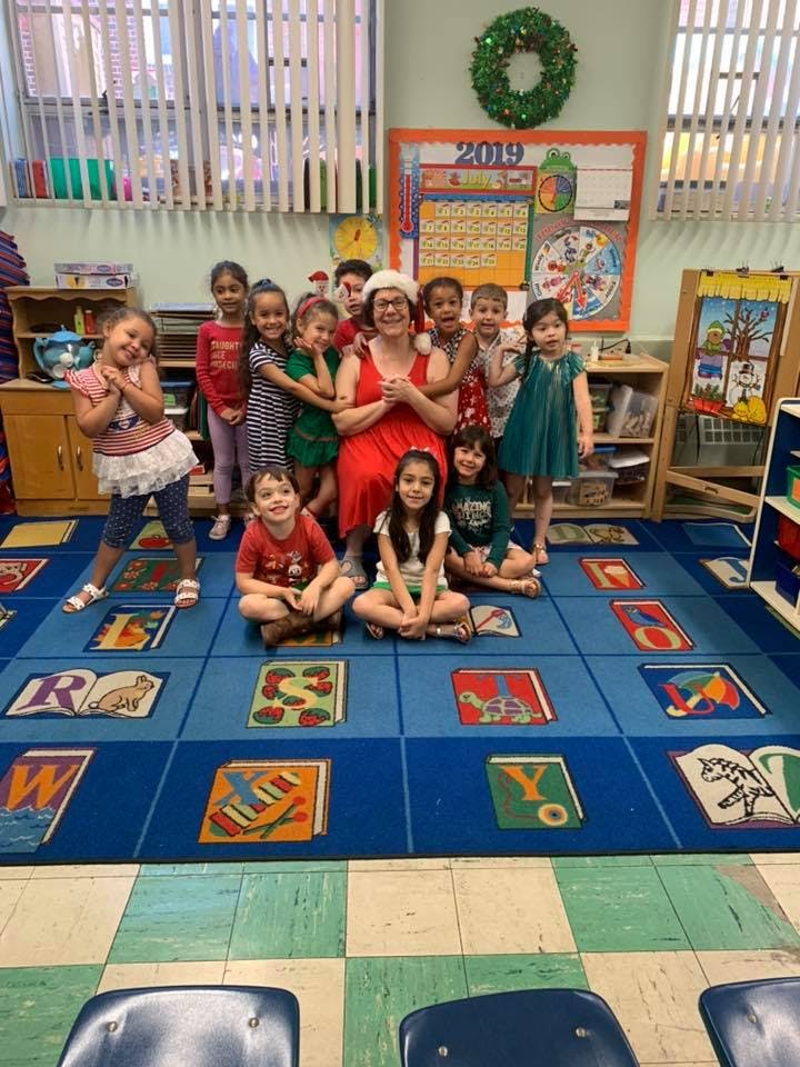 Adult in Santa hat with a group of children in a classroom