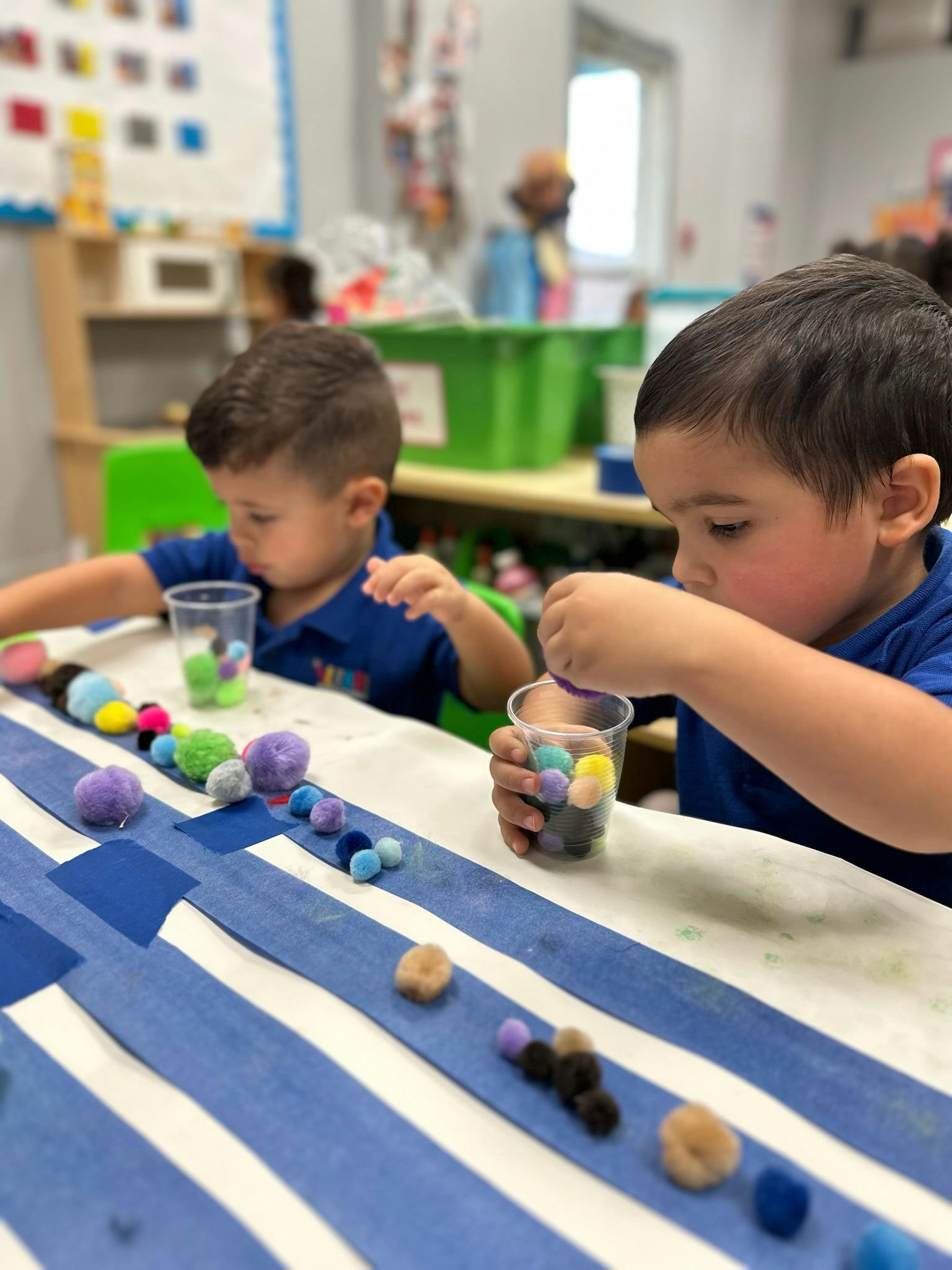 Children placing small pom-poms into cups during a classroom activity