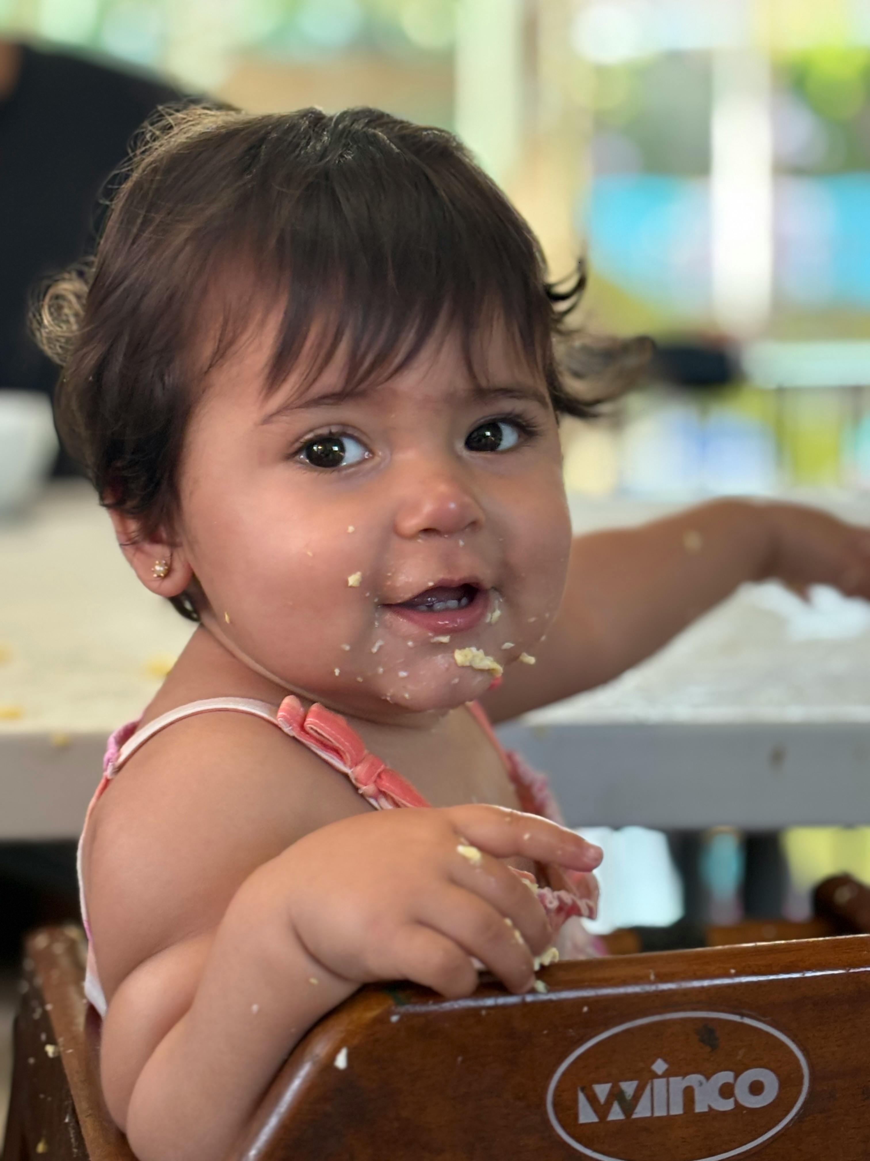 Child with food on face and hands in a high chair