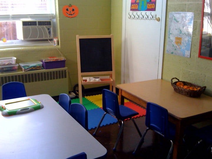 Classroom with tables, chairs, and a chalkboard easel