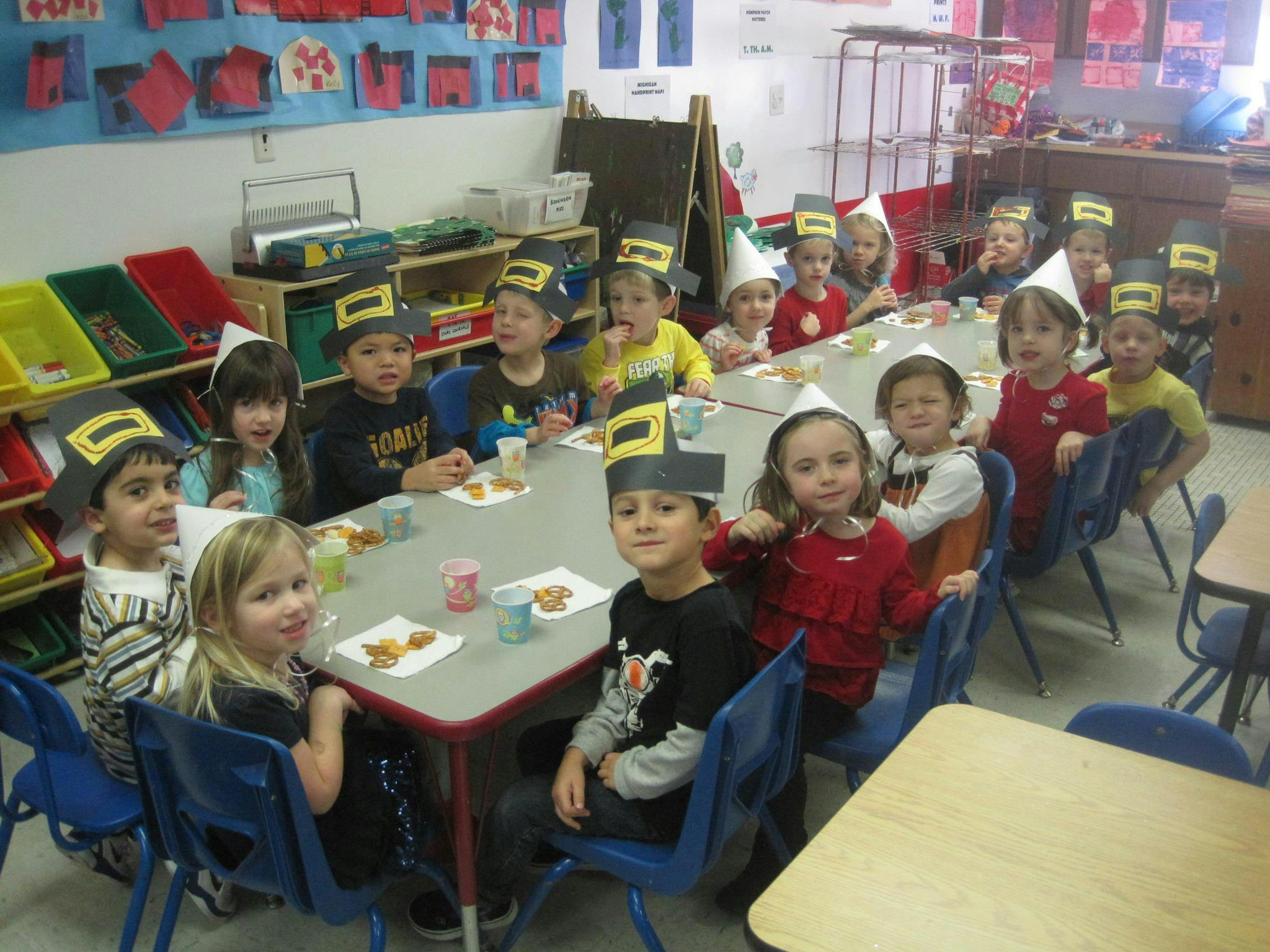 Children wearing hats sitting at tables in a classroom