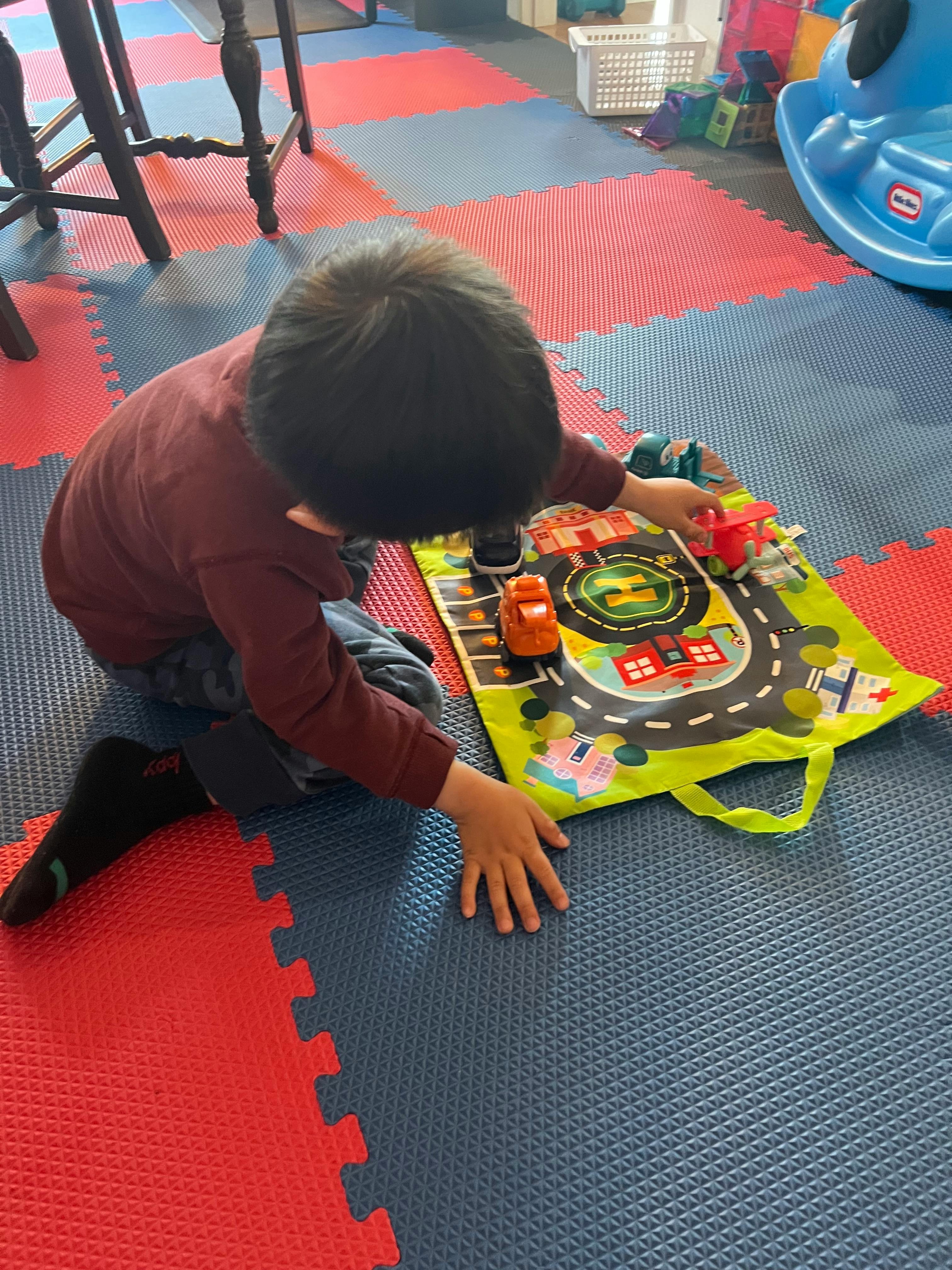 Child playing with toy cars on a road map mat