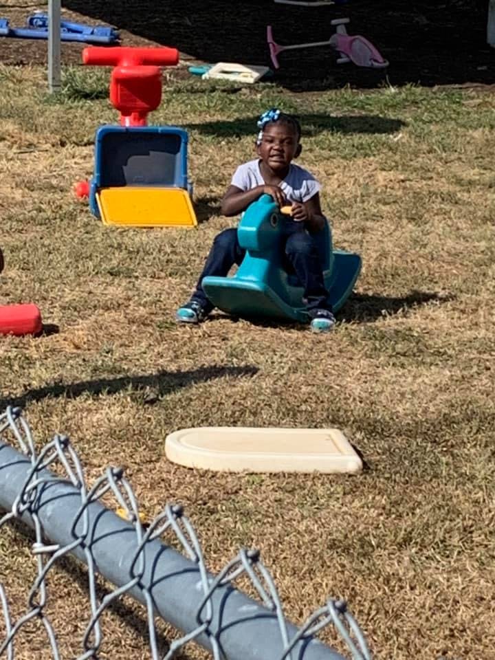 Child on a teal rocking horse toy outdoors