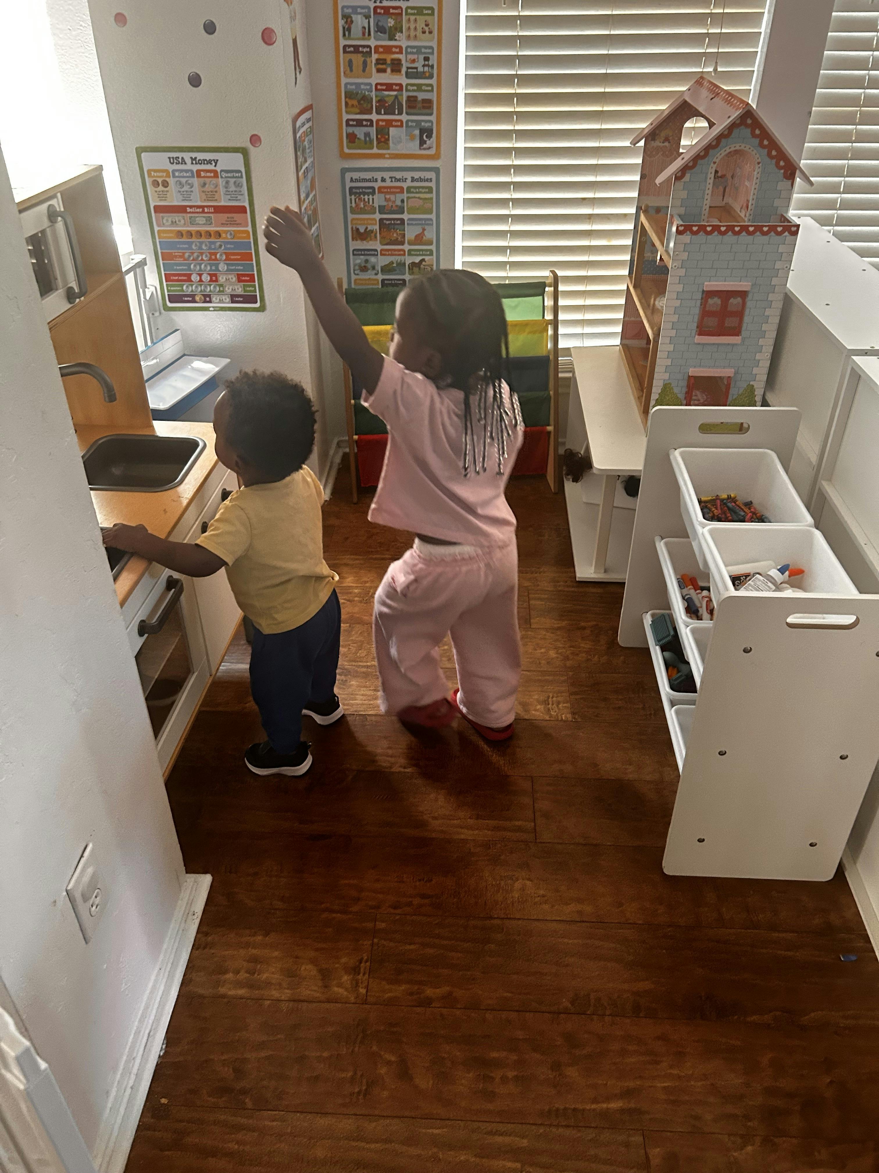 Two children playing with a toy kitchen in a playroom