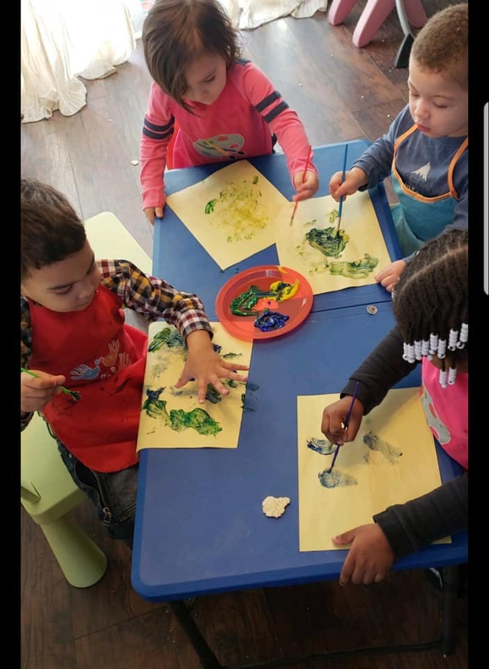 Four children painting at a blue table
