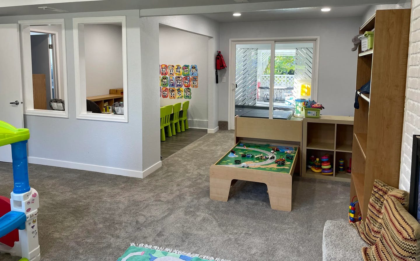 Playroom with a train table, shelves, and a view into another room with small chairs