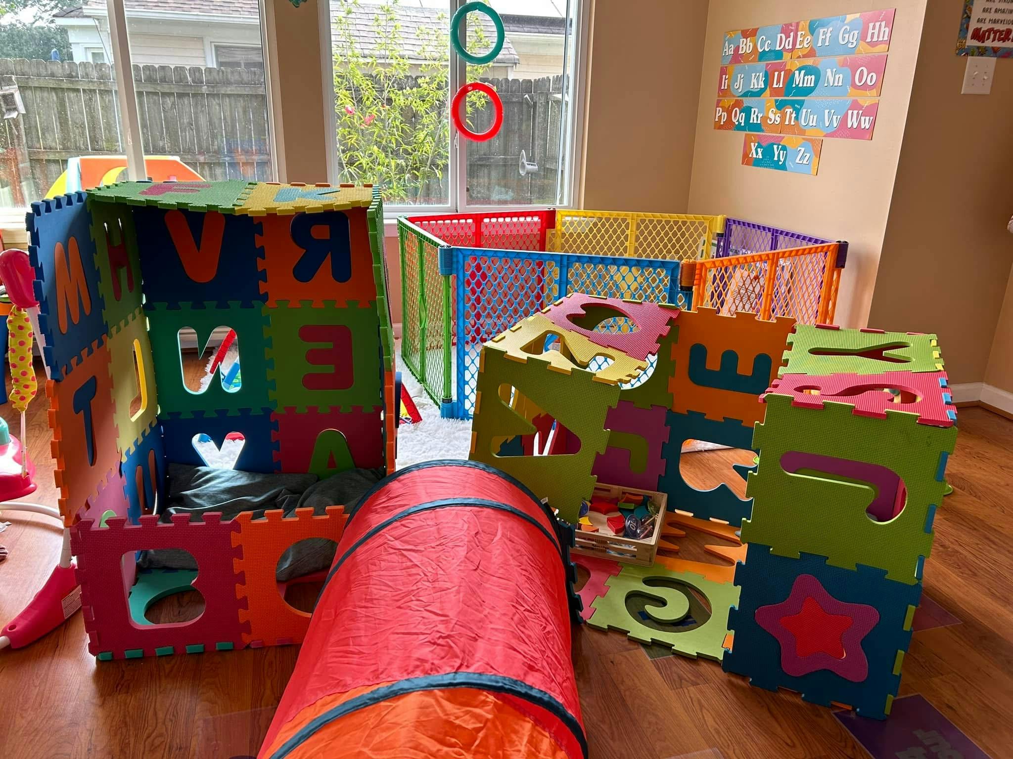 Colorful playroom with foam block structures, playpen, and a red tunnel