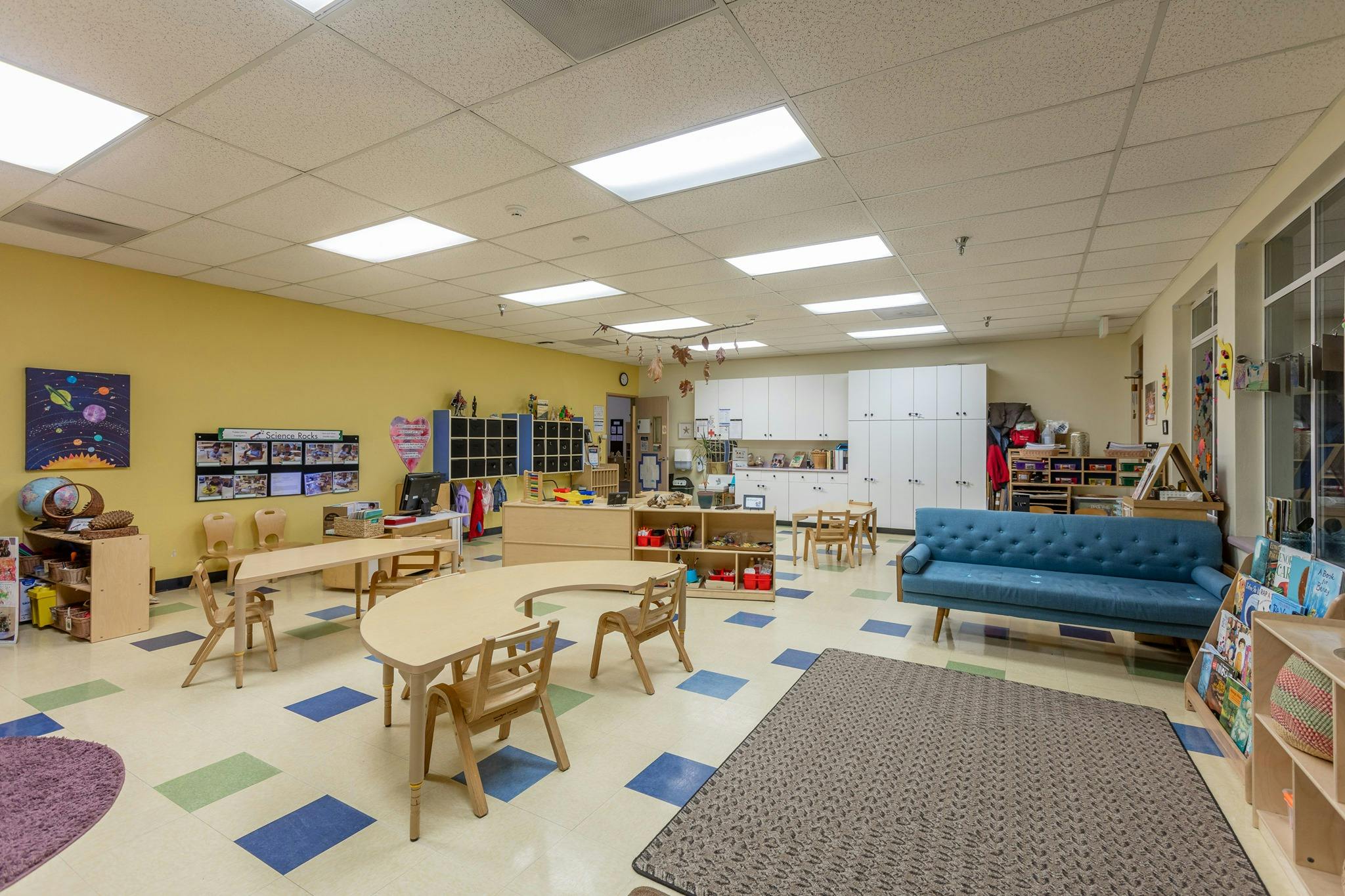 Classroom with tables, chairs, and a blue sofa