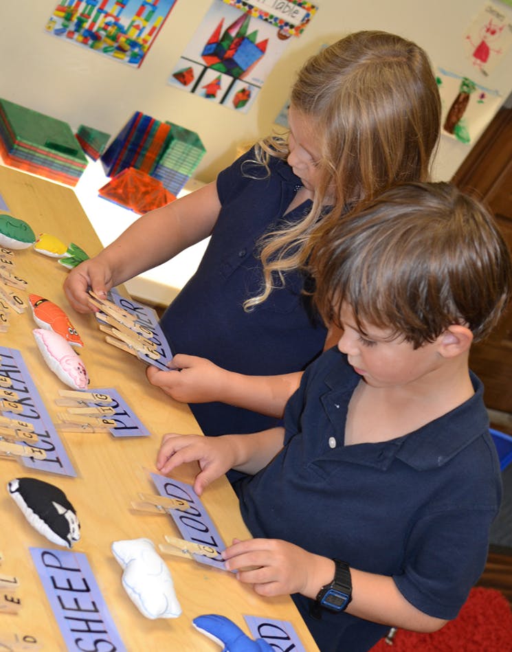 Two children playing with learning materials at a table