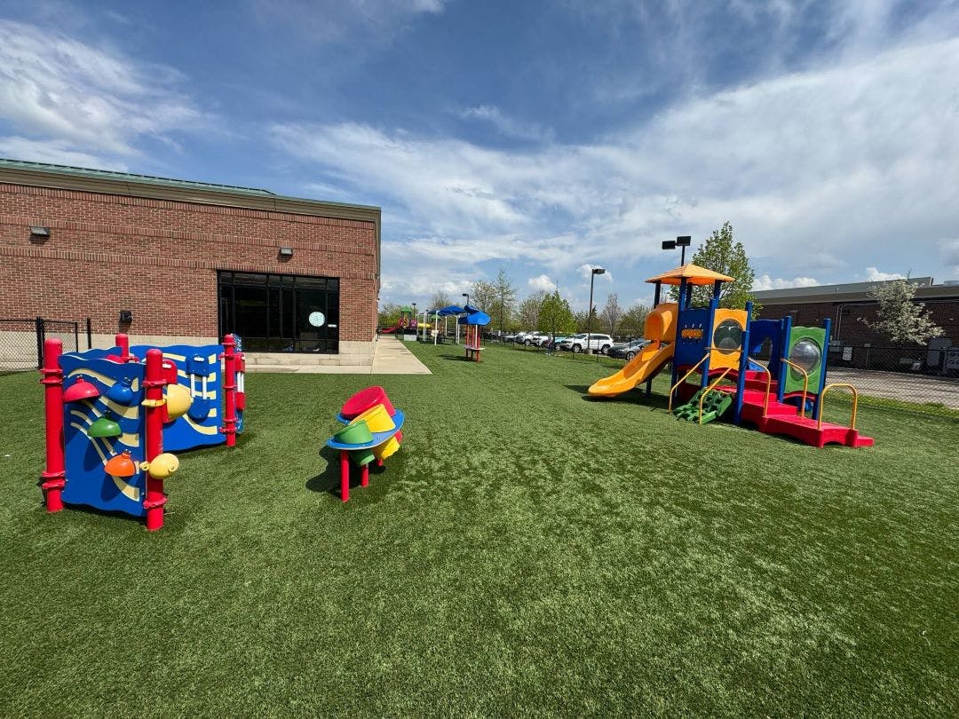Playground with multiple colorful play structures on green artificial turf
