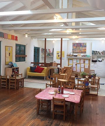Classroom with small tables and chairs, a yellow couch, and shelves