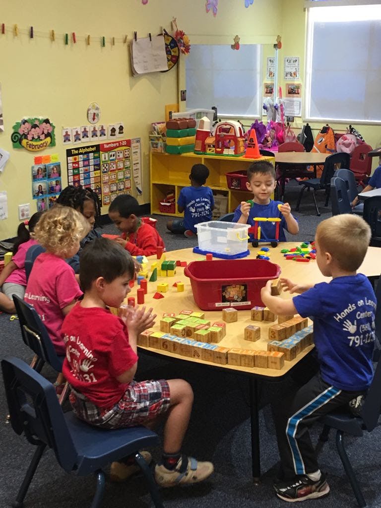Children playing with blocks at a table in a classroom