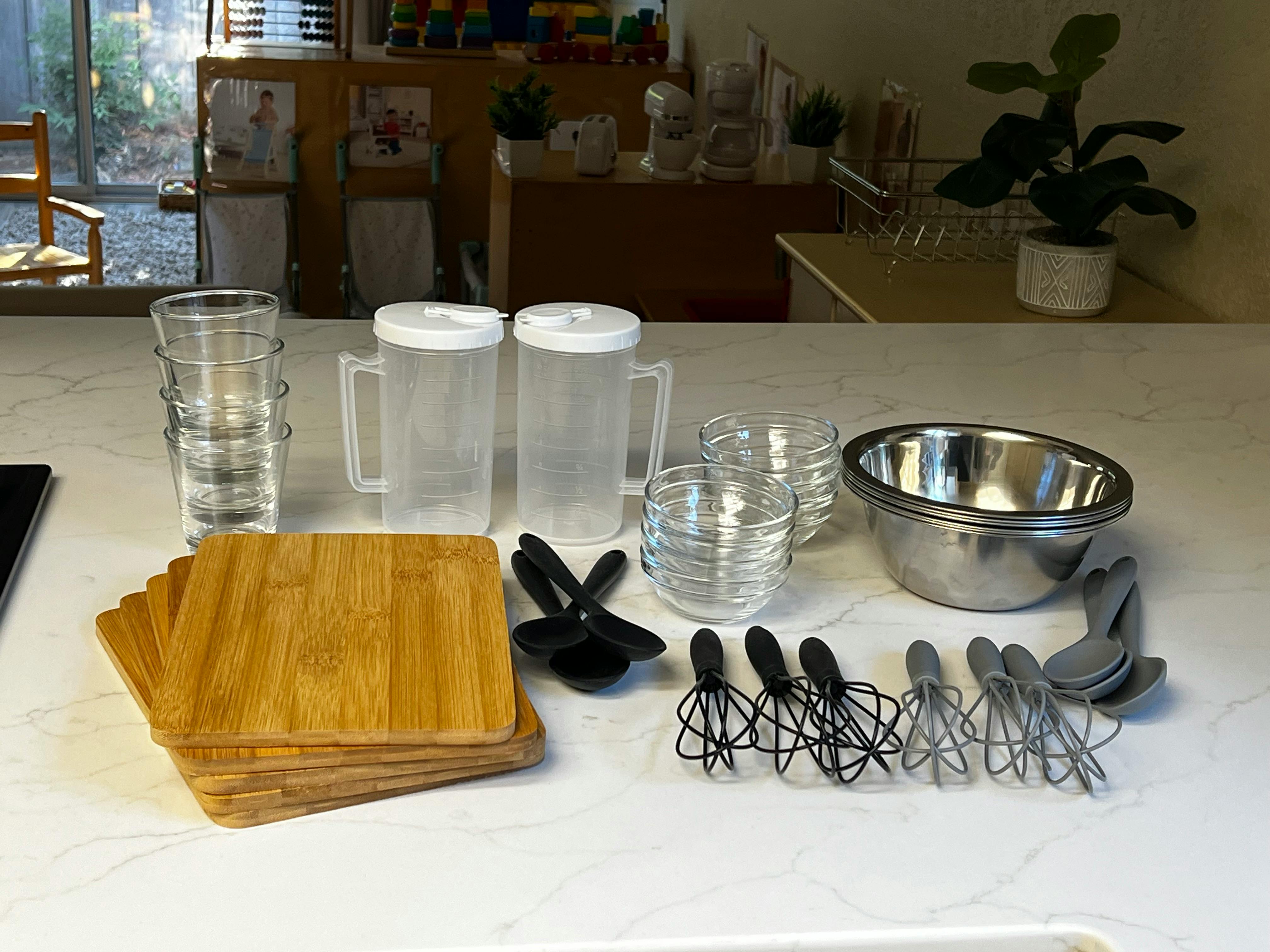 Kitchen counter with cutting boards, pitchers, glasses, bowls, and whisks