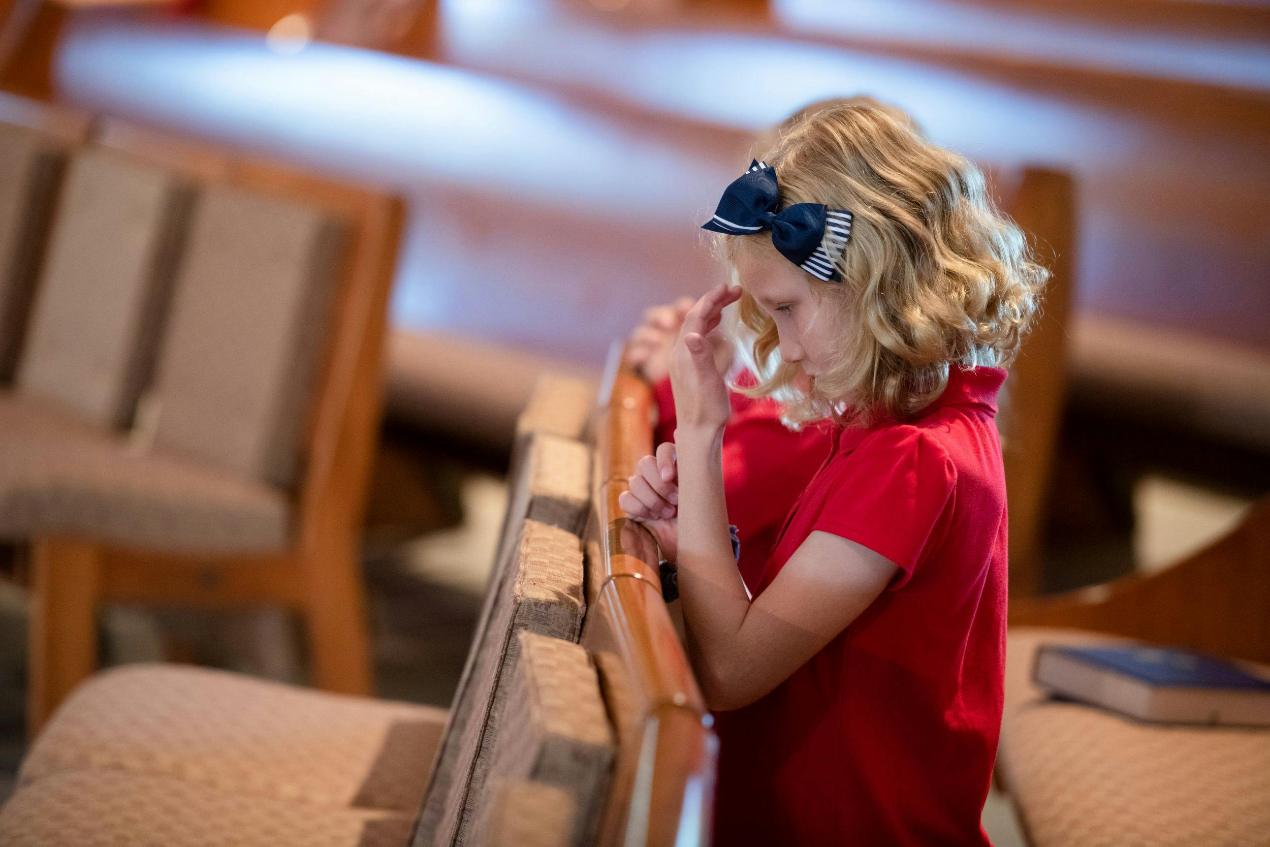 Child kneeling at a pew