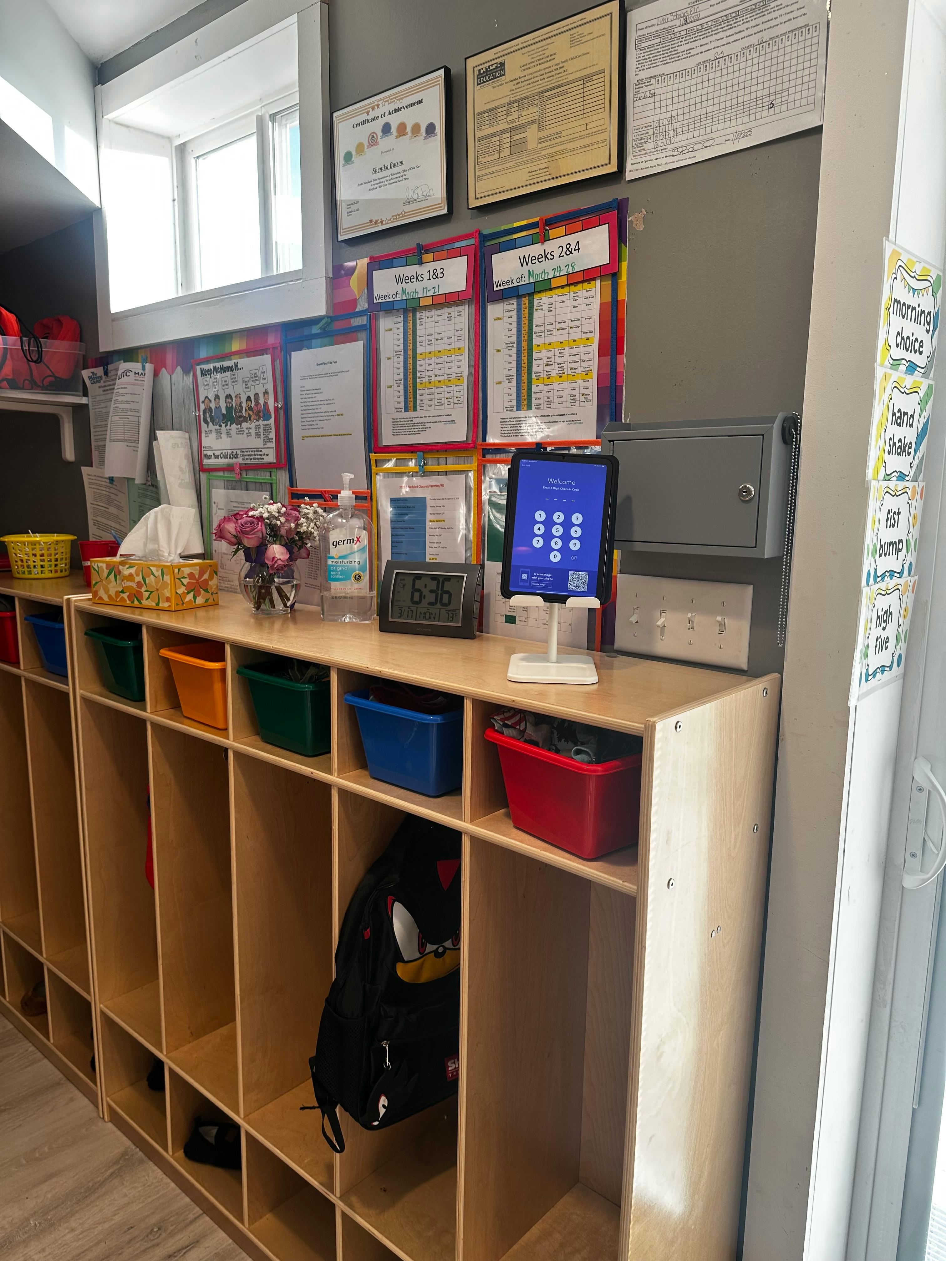 Wooden cubbies with colorful bins and a tablet on a counter