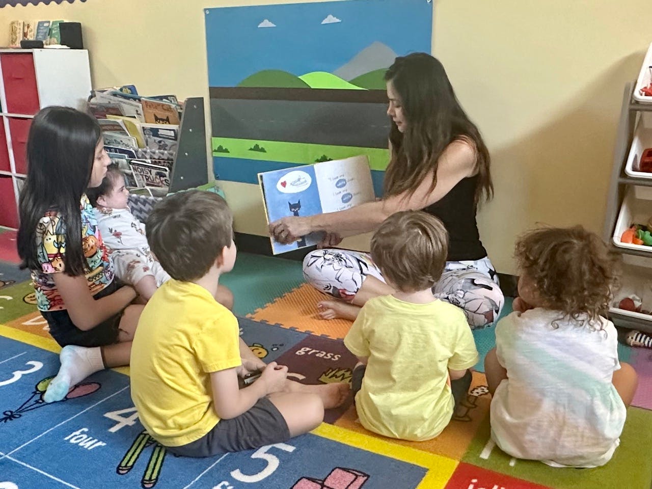 Person reading a book to children in a classroom