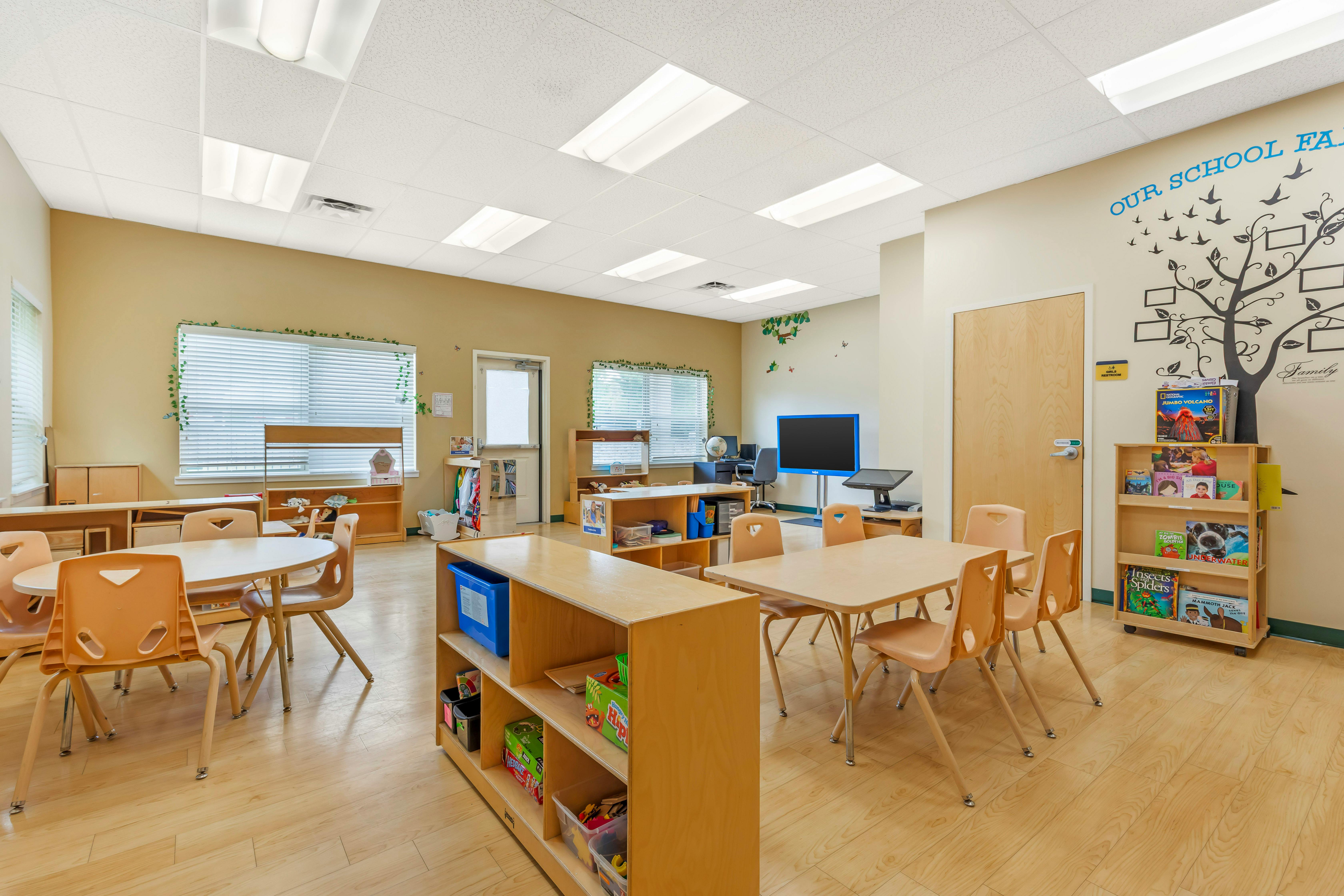 Empty preschool classroom with tables, chairs, and learning resources