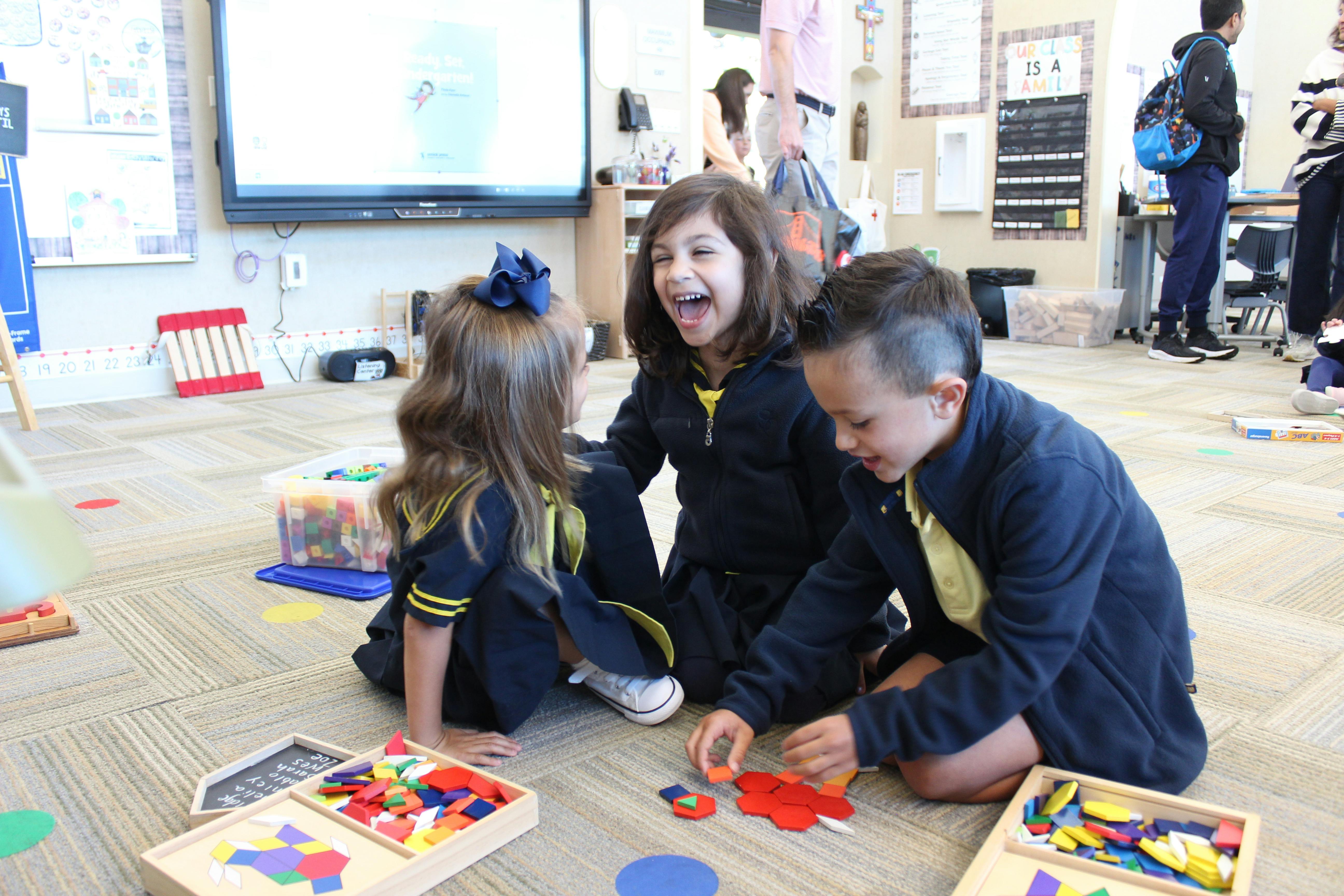 Three children playing with colorful shapes on the floor