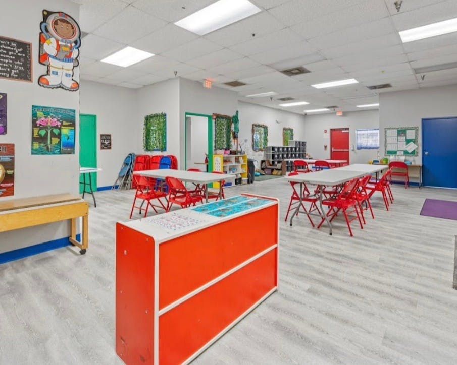 Classroom with multiple tables and red chairs