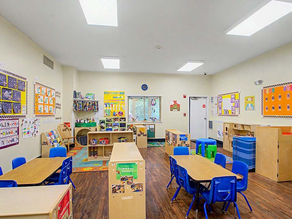 Classroom with small tables and chairs, toys, and colorful artwork on walls