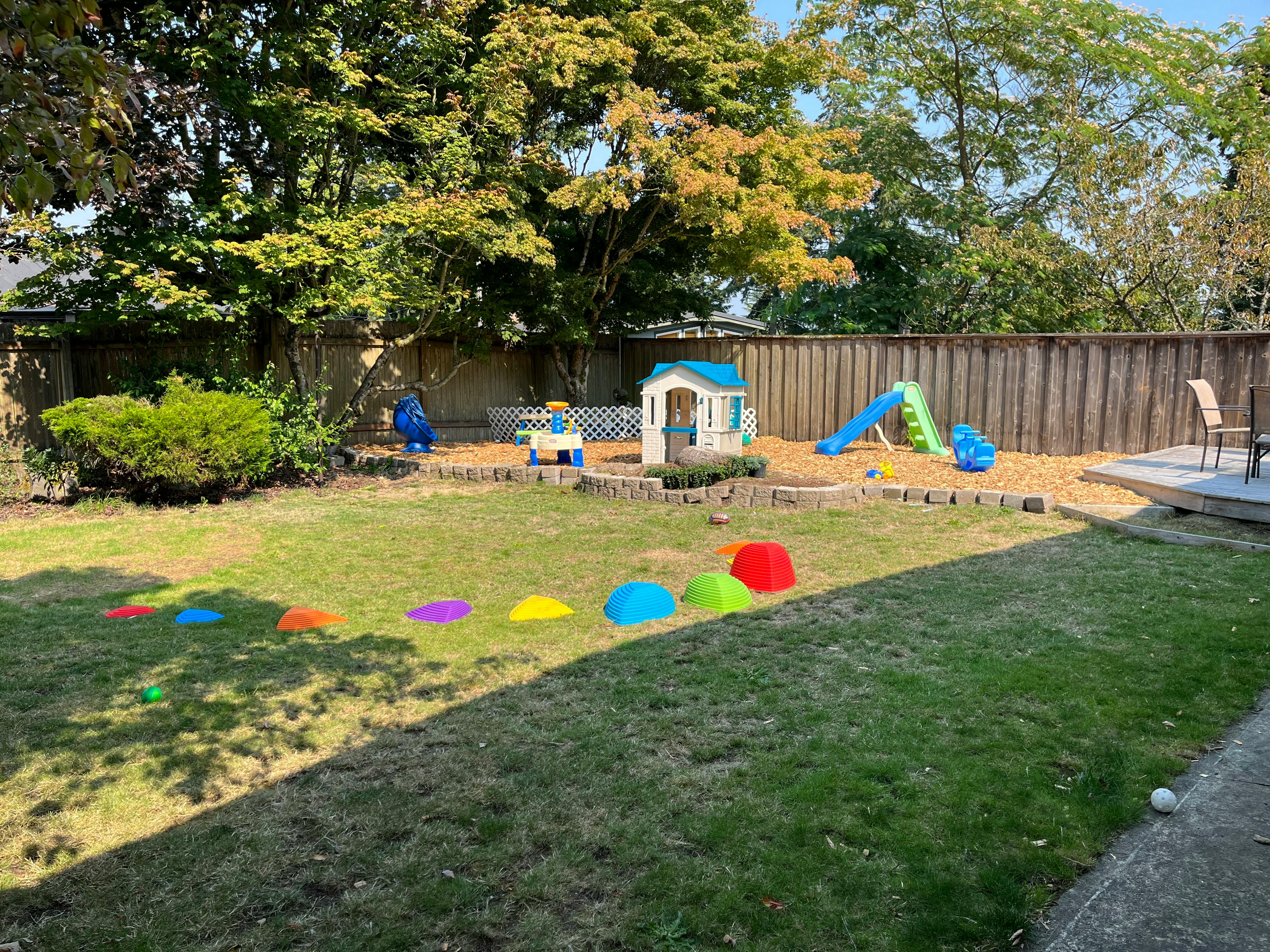 Backyard with playhouse, slide, and colorful markers on the grass