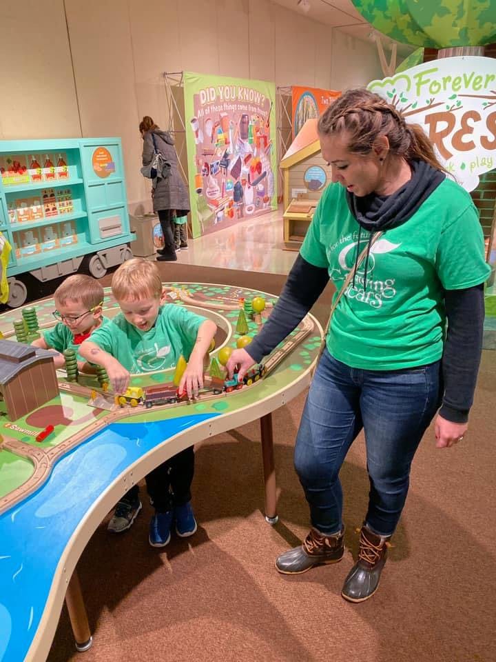 Adult and two children playing with a toy train set