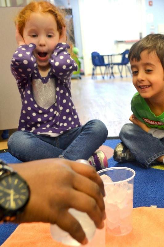 Child with hands over ears, another child smiling, and a hand holding a cup