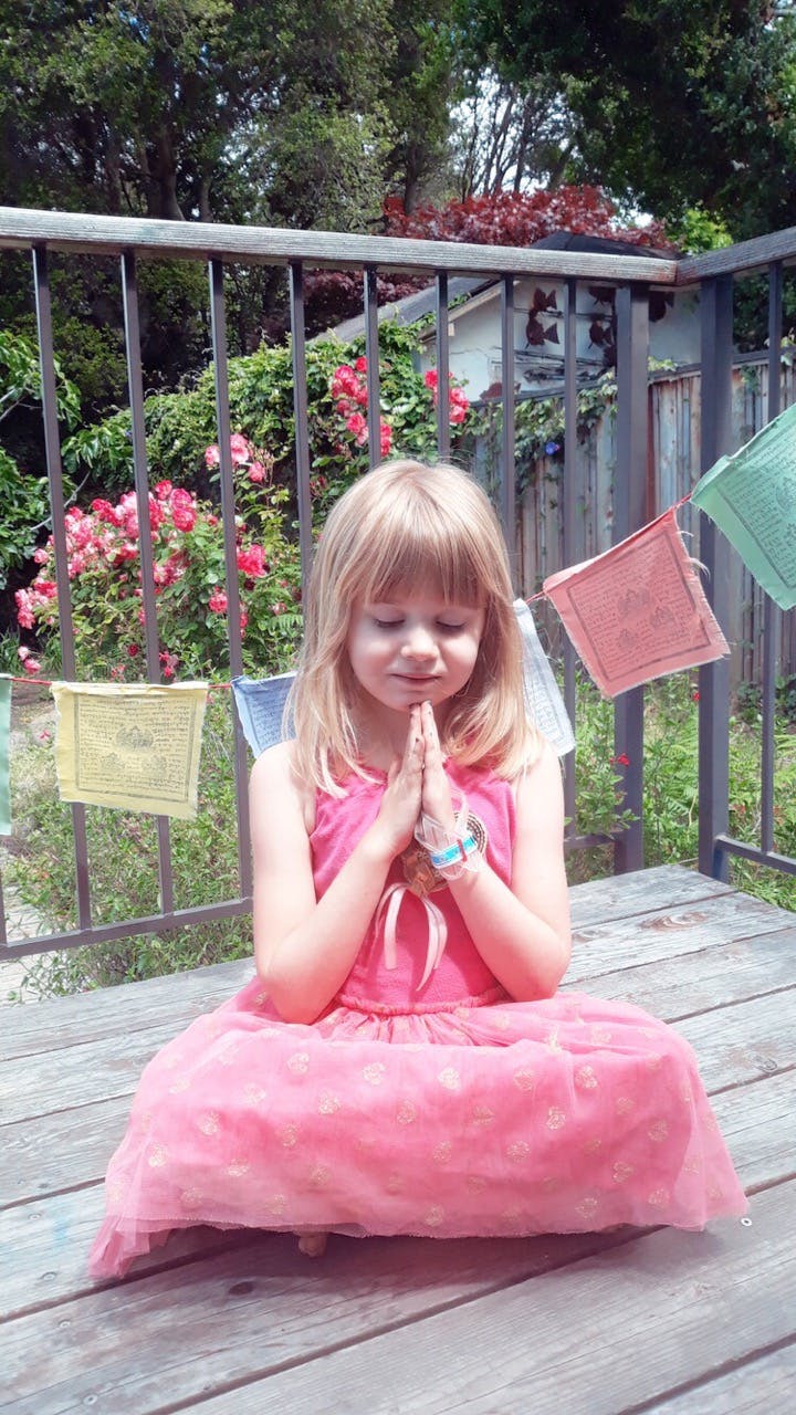 Child in pink dress sitting with hands together