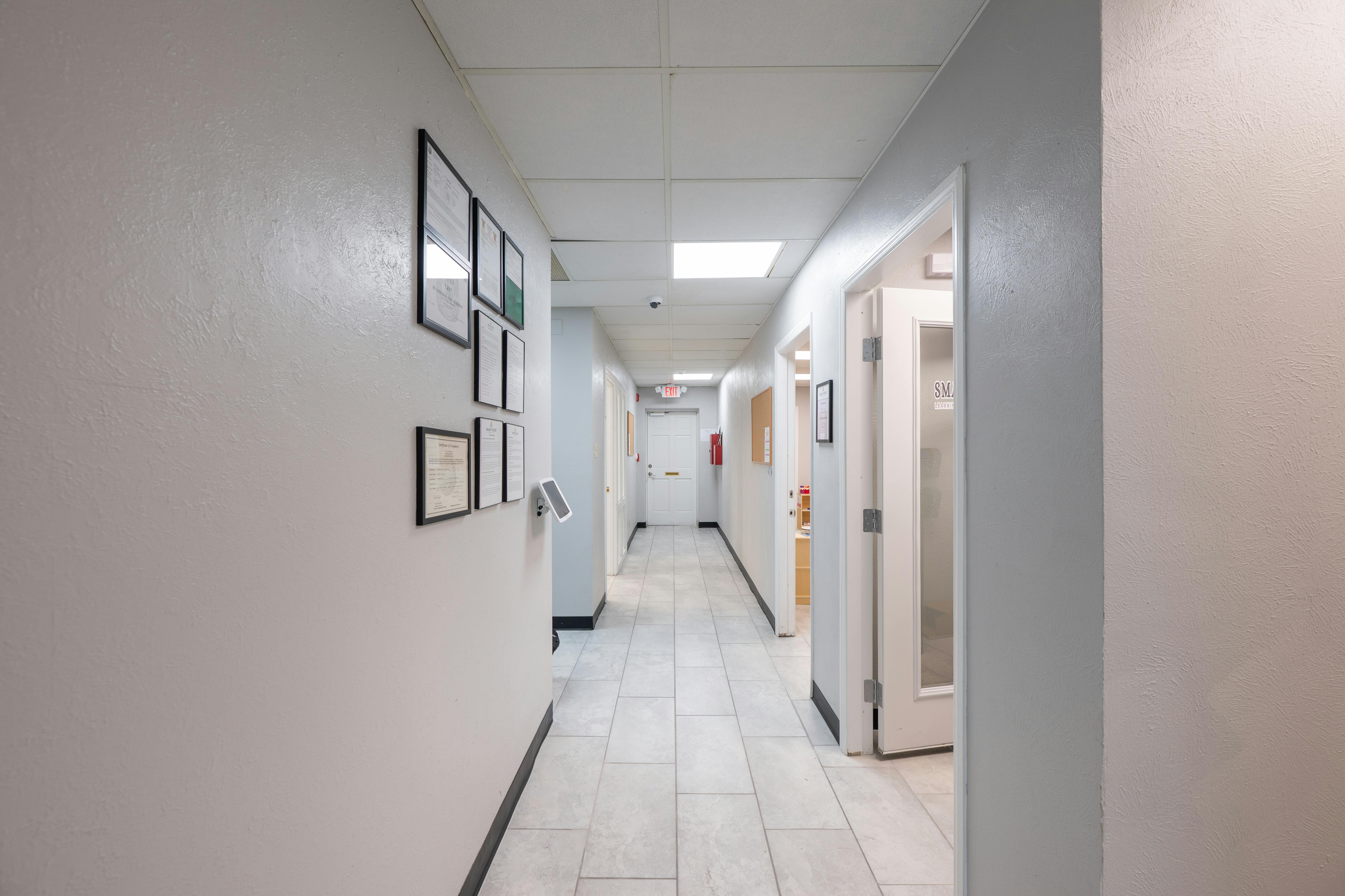 Long hallway with white walls and framed pictures